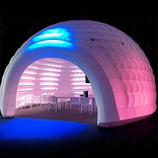 A large inflatable dome event space with a white textured exterior and glowing pink interior, illuminated by blue and pink LED lighting against a dark background.