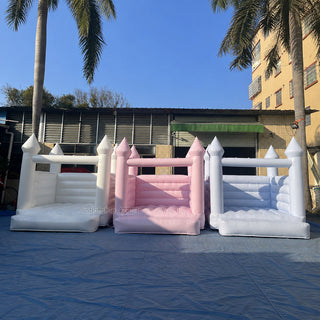 Three white and pink mini inflatable bounce houses outdoors